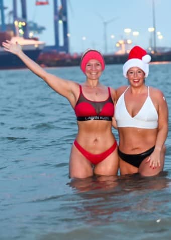 zwei Frauen stehen hüfttief im eisigen Wasser, um ein Lächeln und Herzenswärme zu verteilen