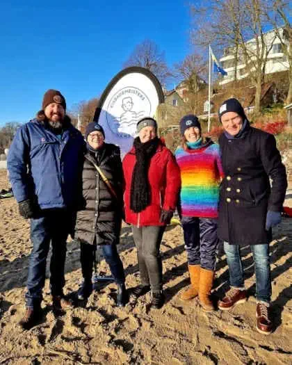 drei Frauen und zwei Männer -das Orga Team der Eisbademeisters-Hamburg- stehen am Elbstrand Övelgönne