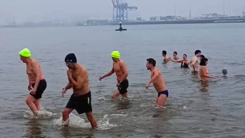 Gruppe von Männern bibbert für den guten Zweck im kalten Wasser