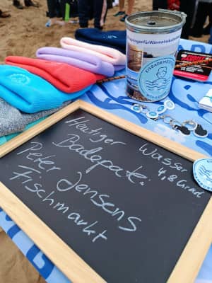 Infostand mit Mützen, Spendendose und Bekanntgabe Badepate und Wassertemperatur