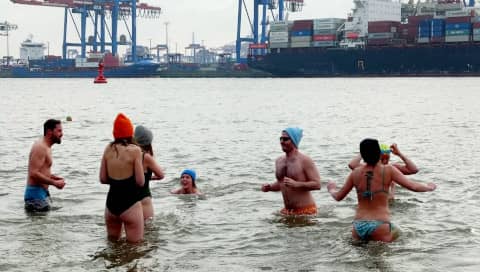 Männer und Frauen sind hüfttief im eisigen Wasser.
