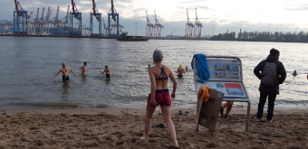 Frau in Badeklamotte geht im Winter baden