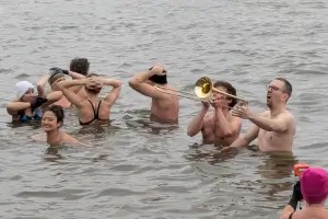 Menschen im eisigen Wasser, einer davon spielt Posaune