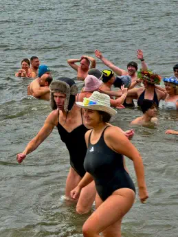 Menschengruppe mit phantasievollen Hüten und Mützen nehmen ein Kaltbad