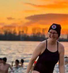 Frau in Badeanzug und Mütze kommt aus der kalten Elbe