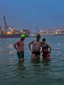 Zwei Männer und eine Frau knietief im Wasser bei winterlichen Temperaturen