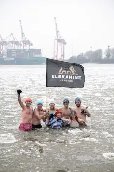 7 Frauen und Männern posieren mit einer Fahne von Elbkamine vor der Kamera, um ein gemeinsames Foto zu machen.