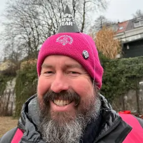 Mann mit Eisbademeisters Mütze und obendrauf noch ein weiteres Hütchen mit der Aufschrift: Happy New Year