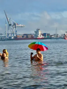Mann mit Schirm im Eiswasser macht ein Selfi