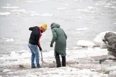 Zwei Leute errichten eine Schneise (befreien den Weg vom Eis), damit die Eisbader gefahrenfrei vom Strand ins Wasser gehen können.