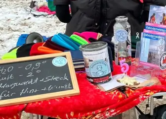 Geburtstagstisch mit Mützen, Infotafel, Spendenbox und einer 5.